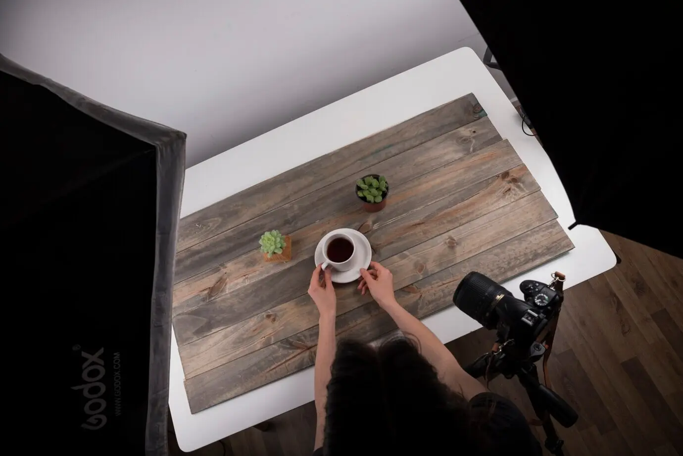 Ansicht von oben auf einen Fotografen, der eine Tasse Tee für eine Aufnahme im Studio arrangiert.